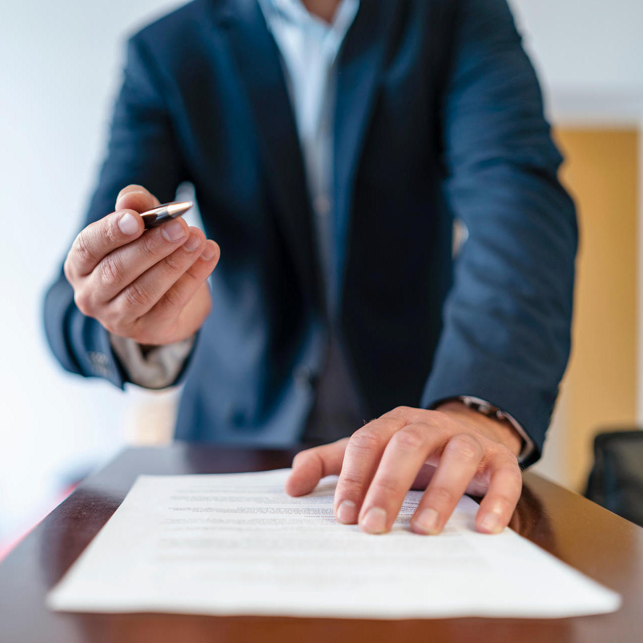 Close-up of businessman in office presenting ballpen and contract